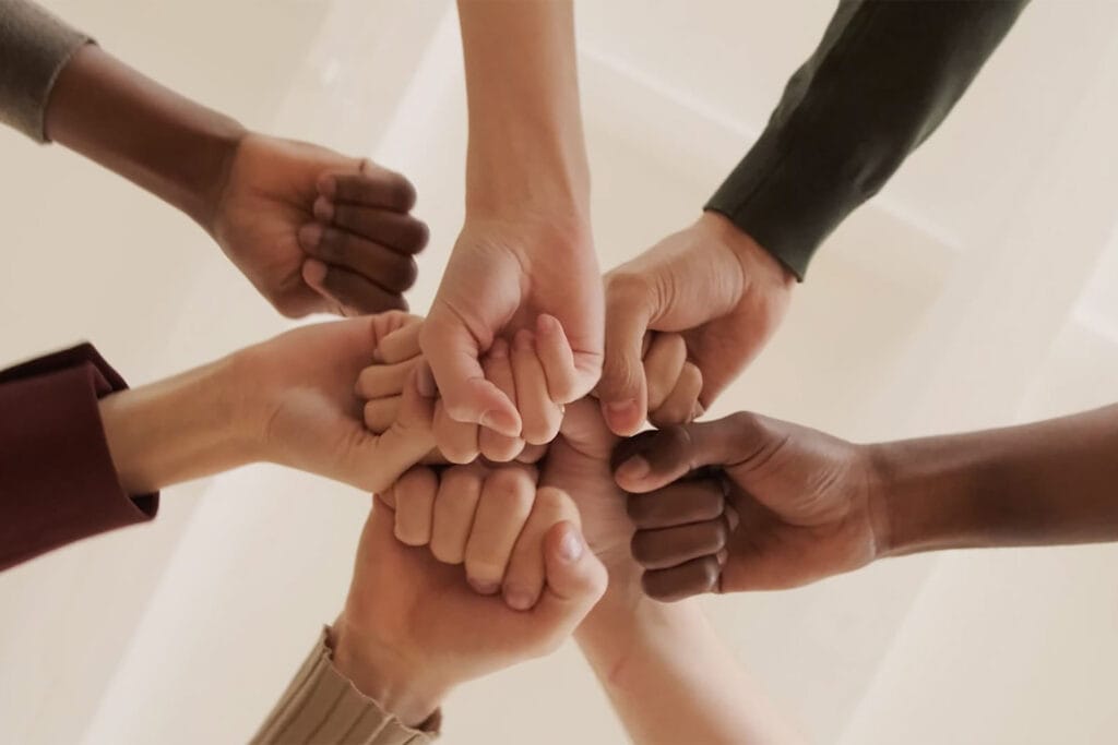 Diverse team members' hands joined together in a show of teamwork and unity.